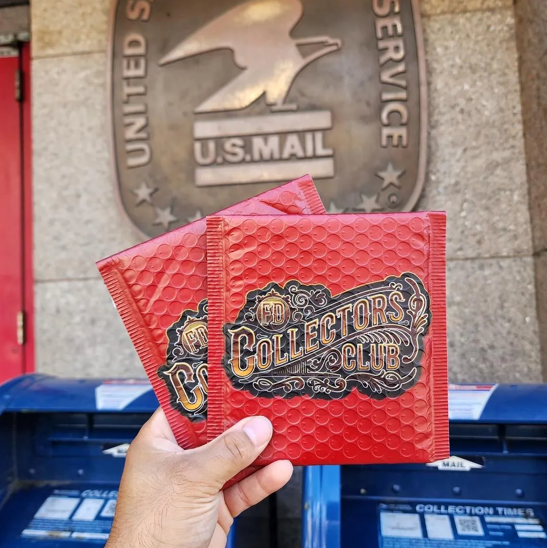 An FD Collector's Club mailer held in front of a postbox