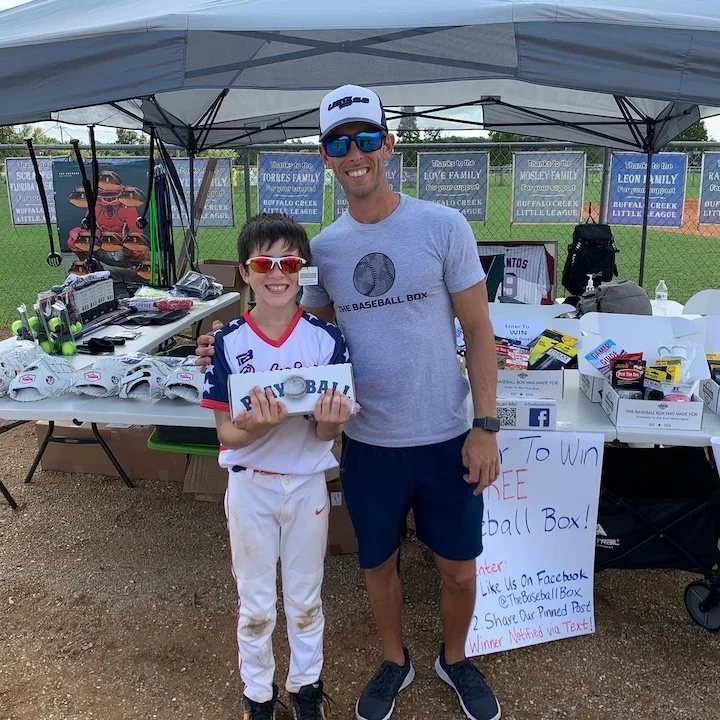 A young player and coach at The Baseball Box tent